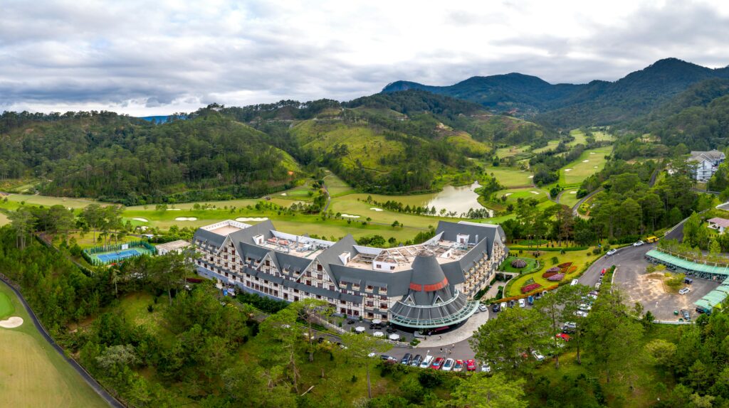pexels-photo-12389418-12389418 Scenic aerial view of a luxurious mountain resort surrounded by lush greenery and a golf course.