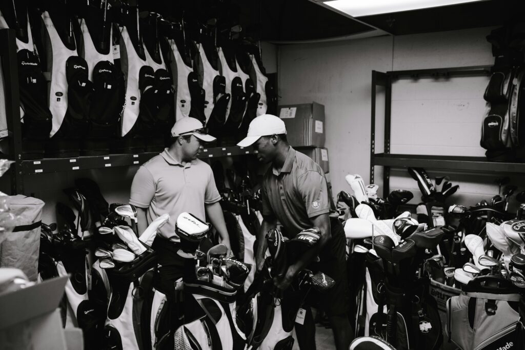 pexels-photo-1325706-1325706 Two men sorting and organizing golf bags and clubs in a storage room.