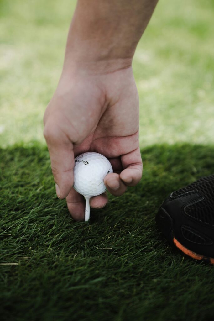 pexels-photo-1325745-1325745 A person carefully placing a golf ball on a tee, ready for a perfect shot.